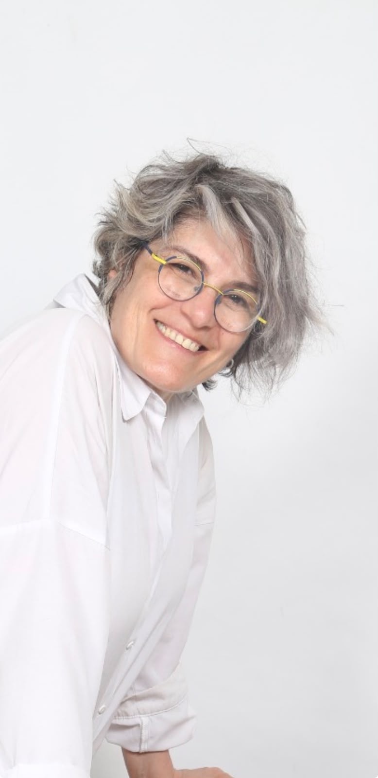 Doress Naffaa smiling, wearing glasses and a white shirt